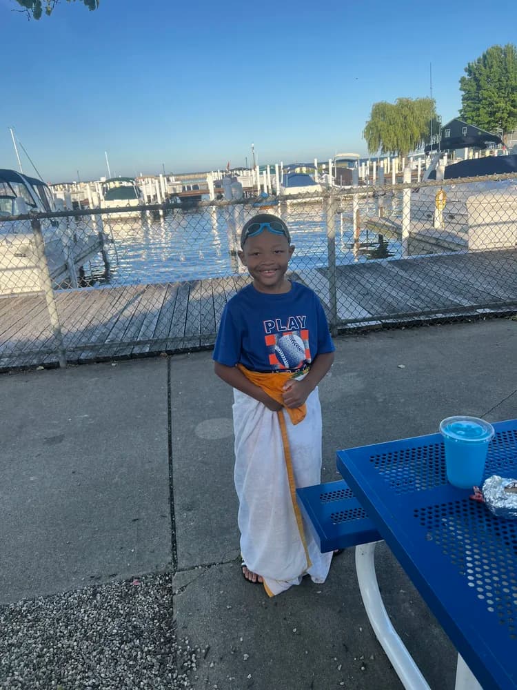 Junior smiling at the marina wrapped in a towel after swimming